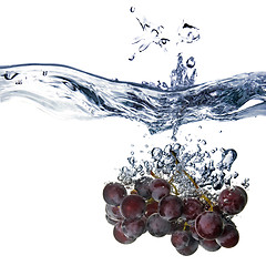 Image showing blue grape dropped into water with splash isolated on white