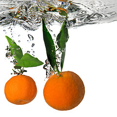 Image showing tangerine dropped into water with bubbles on white