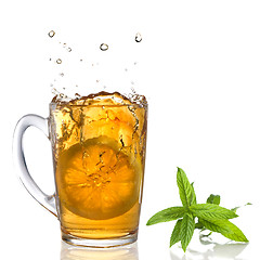 Image showing lemon dropped into tea cup with splash and mint isolated on whit