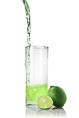 Image showing green juice with lime pouring into glass isolated on white