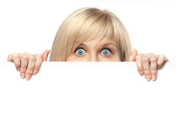 Image showing surprised young woman holding white empty paper isolated on whit