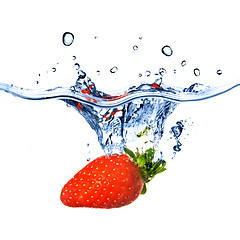 Image showing Fresh strawberry dropped into blue water with splash isolated on