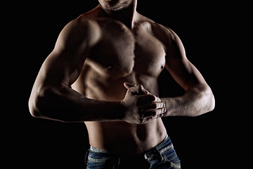 Image showing Muscular naked man on black. Focus and hands