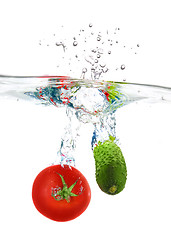 Image showing red tomato and green cucumber dropped into water isolated on whi