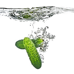 Image showing green cucumbers dropped into water isolated on white