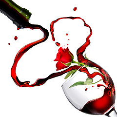 Image showing Heart from pouring red wine in goblet with red rose isolated on 