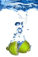 Image showing Fresh lime dropped into water with bubbles isolated on white