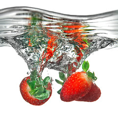 Image showing Fresh strawberry dropped into water with splash isolated on whit