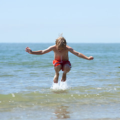 Image showing Boy jumps over wave