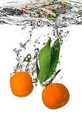 Image showing tangerine dropped into water with bubbles on white