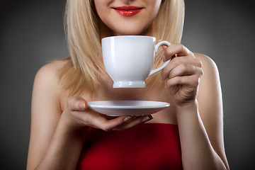 Image showing woman in red holding cup and smiles