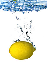 Image showing Fresh lemon dropped into water with bubbles isolated on white