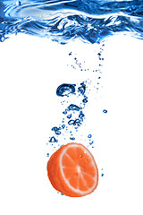 Image showing Fresh grapefruit dropped into water with bubbles isolated on whi