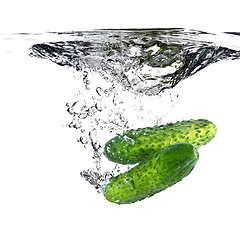 Image showing green cucumbers dropped into water isolated on white