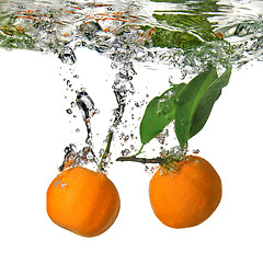 Image showing tangerines dropped into water with bubbles on white