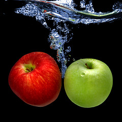 Image showing apples dropped into water with splash isolated on black