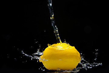 Image showing Fresh lemon and water splash isolated on black