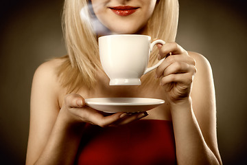 Image showing woman in red holding cup and smiles