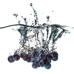 Image showing blue grape dropped into water with splash isolated on white