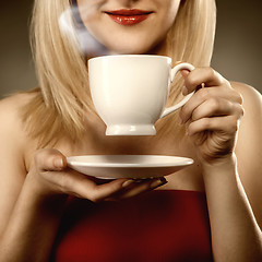 Image showing woman in red holding cup and smiles