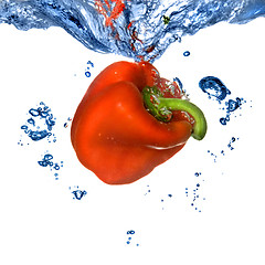 Image showing Red pepper dropped into blue water with bubbles isolated on whit