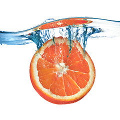 Image showing Fresh grapefruit dropped into water with splash isolated on whit