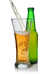 Image showing Beer pouring from into glass isolated with bottle on white