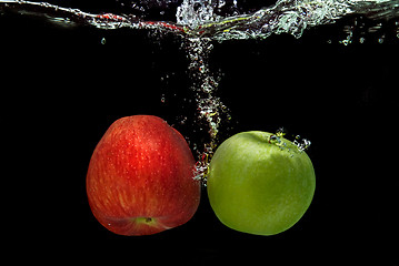 Image showing ref and green apple dropped into water with splash isolated on b