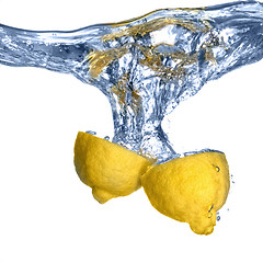 Image showing Fresh lemon dropped into water with bubbles isolated on white