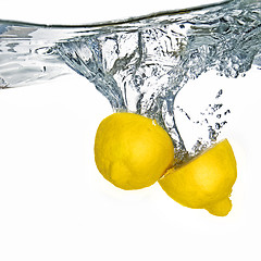 Image showing Fresh lemon dropped into water with bubbles isolated on white