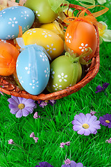 Image showing color easter eggs in basket on the green grass
