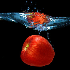 Image showing red apple dropped into water with splash isolated on black