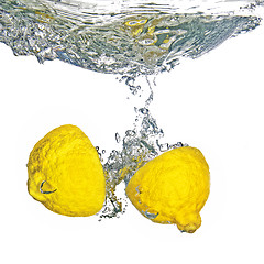 Image showing Fresh lemon dropped into water with bubbles isolated on white