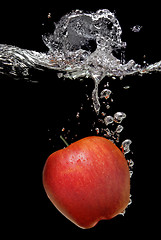 Image showing green apple dropped into water with splash isolated on black