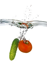 Image showing red tomato and green cucumber dropped into water isolated on whi