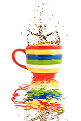 Image showing splash of tea in color cup with reflection