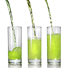 Image showing green juice pouring into glass isolated on white