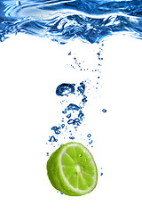 Image showing Fresh lime dropped into water with bubbles isolated on white