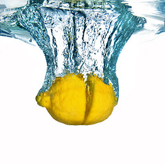 Image showing Fresh lemon dropped into water with bubbles isolated on white