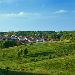 Image showing Green meadow against blue sky and small town