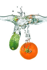 Image showing red tomato and green cucumber dropped into water isolated on whi