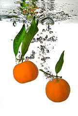 Image showing tangerine dropped into water with bubbles on white