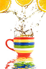 Image showing Lemon juice and splash of tea in color cup with reflection