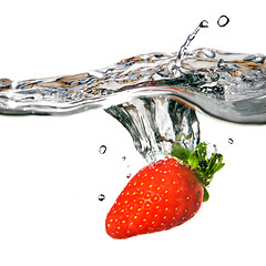 Image showing Fresh strawberry dropped into water with splash isolated on whit