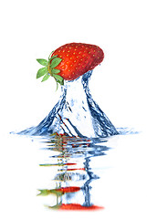 Image showing Fresh strawberry dropped into blue water with splash isolated on