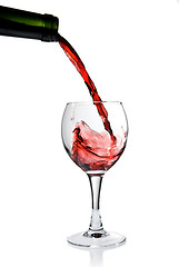 Image showing Pouring red wine in goblet isolated on white