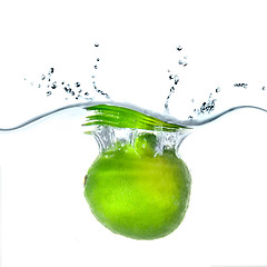 Image showing Fresh lime dropped into water with bubbles isolated on white