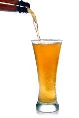 Image showing Beer pouring from bottle into glass isolated on white