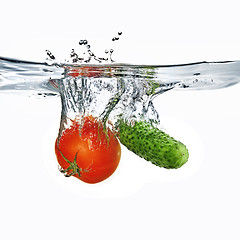 Image showing red tomato and green cucumber dropped into water isolated on whi