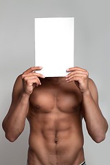 Image showing Muscular naked man holding white empty paper